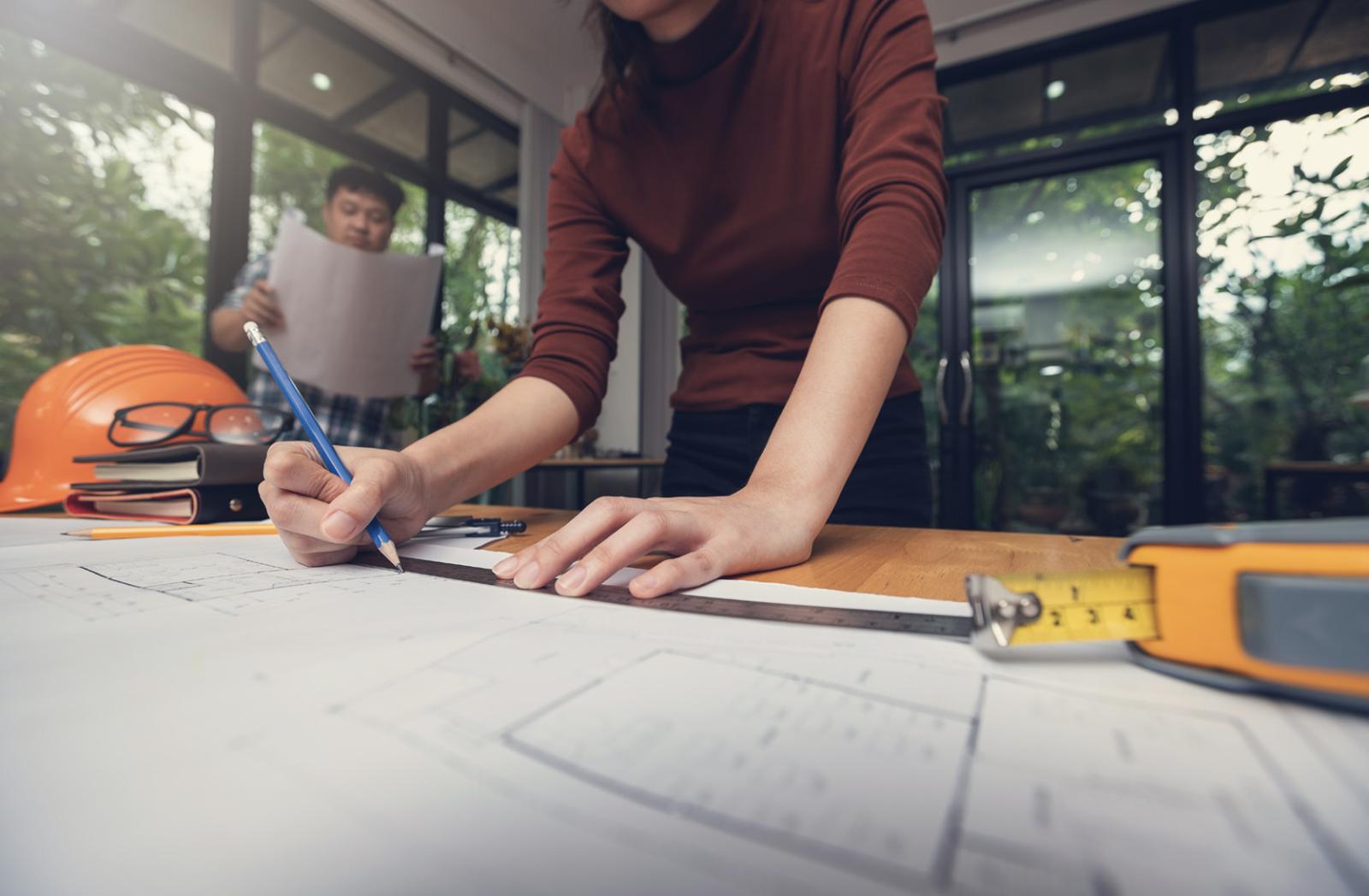 Arquitecta trazando sobre planos en obra